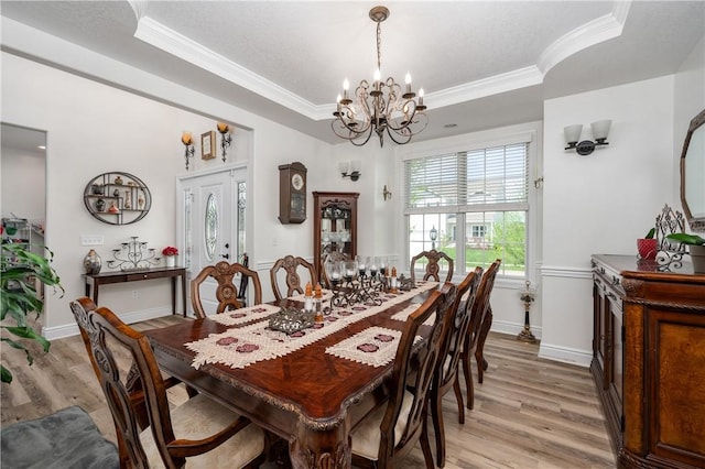 dining area featuring crown molding, light wood-style flooring, baseboards, and a chandelier