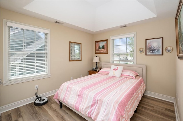 bedroom featuring baseboards, visible vents, and wood finished floors