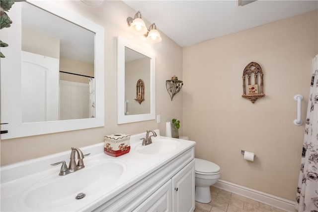 bathroom featuring double vanity, toilet, baseboards, and a sink