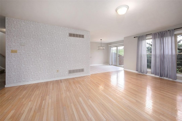 1004 Augusta Ln, Penn Twp Wml, PA 15644 - unfurnished living room with wallpapered walls, light wood-style floors, baseboards, and an accent wall