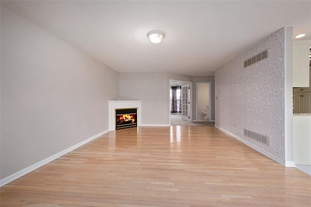 1004 Augusta Ln, Penn Twp Wml, PA 15644 - unfurnished living room with light wood-type flooring, baseboards, and a lit fireplace