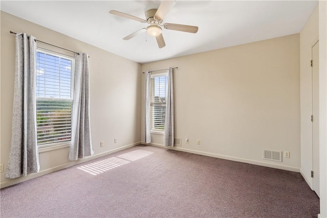 carpeted empty room featuring baseboards, ceiling fan, and visible vents