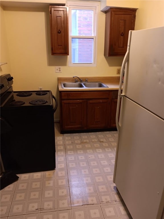 557 Mckean Ave, Donora, PA 15033 - kitchen with freestanding refrigerator, electric range, a sink, light flooring, and light countertops