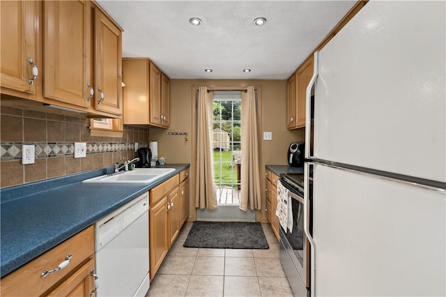 kitchen featuring a sink, dark countertops, white appliances, decorative backsplash, and light tile patterned flooring