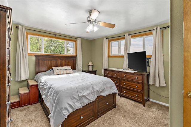 bedroom with multiple windows, light carpet, and baseboards