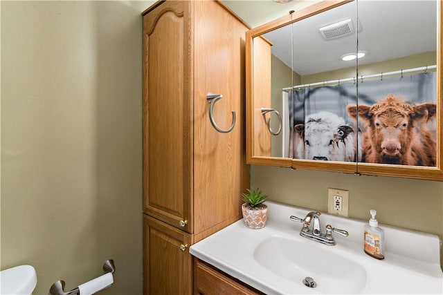 bathroom featuring toilet, vanity, and visible vents