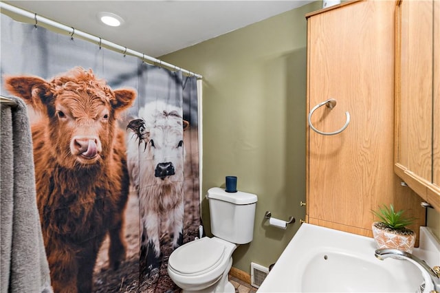 full bathroom with toilet, a shower with curtain, a sink, visible vents, and baseboards