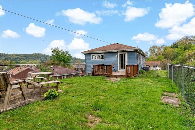 rear view of house featuring a yard, fence, and a deck