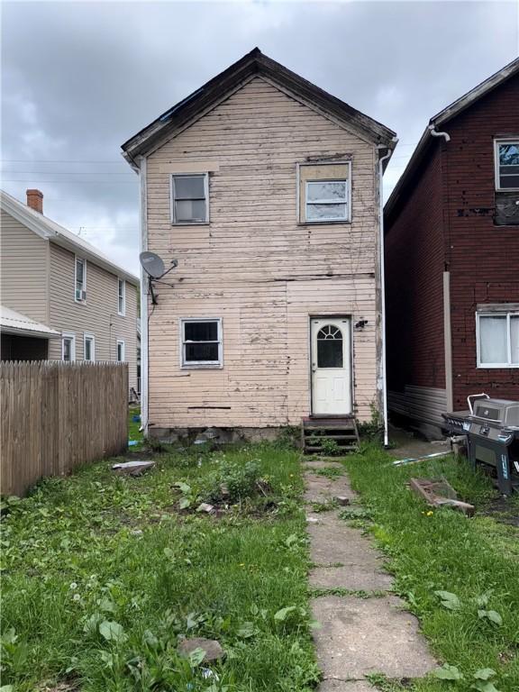 rear view of property featuring entry steps and fence