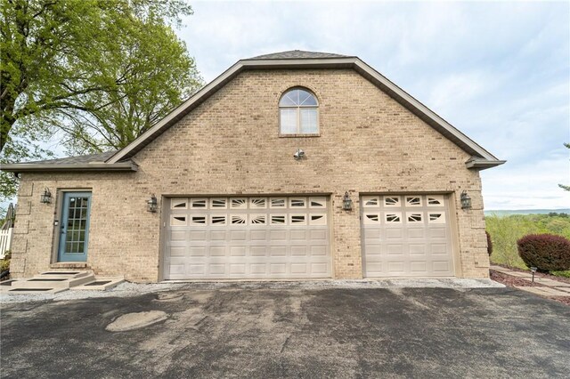 view of home's exterior featuring brick siding, asphalt driveway, and a garage