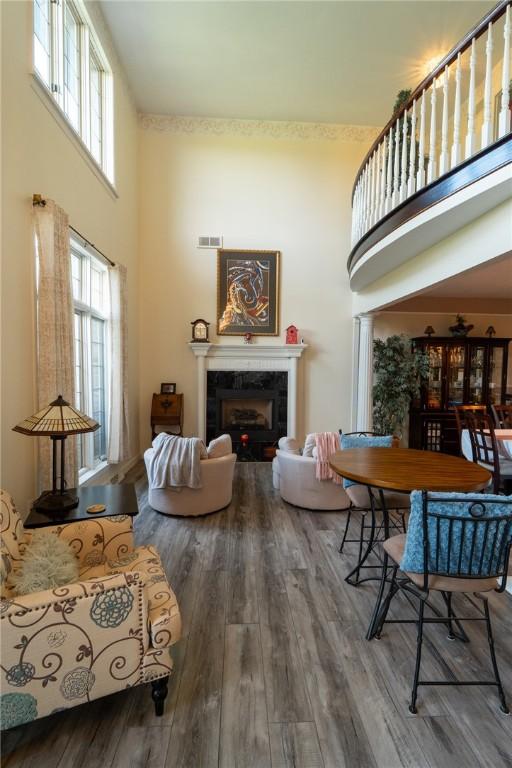 living area with a high ceiling, a tile fireplace, and wood finished floors