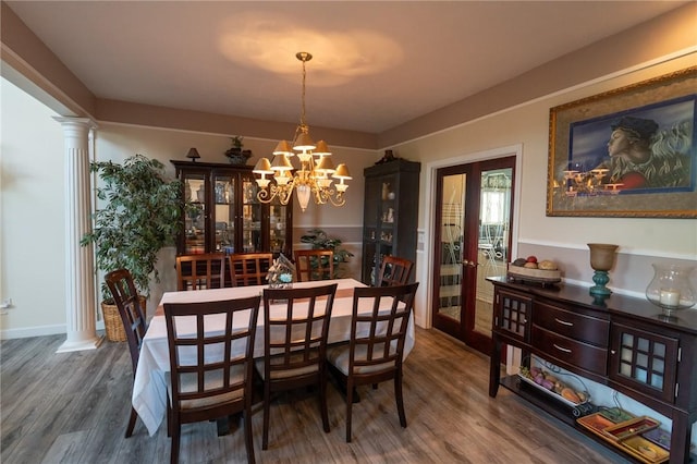 dining area with wood finished floors, a chandelier, and ornate columns