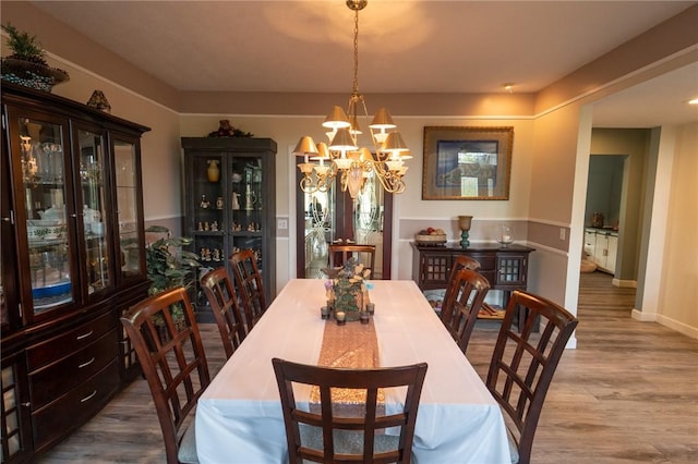 dining room with a chandelier, wood finished floors, and baseboards