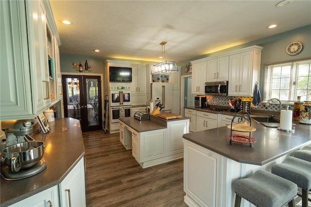 kitchen with appliances with stainless steel finishes, dark countertops, a sink, a peninsula, and recessed lighting
