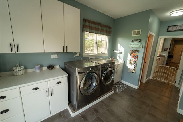 clothes washing area featuring cabinet space, washing machine and clothes dryer, and baseboards