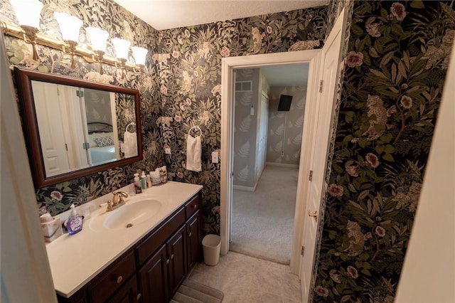 bathroom with wallpapered walls, vanity, and baseboards