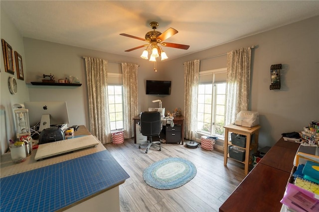 bedroom with an office area, light wood-style flooring, and a ceiling fan