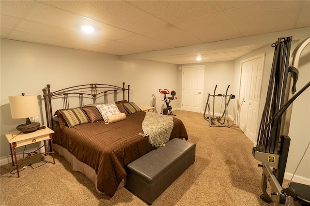 bedroom with light carpet, baseboards, and a paneled ceiling