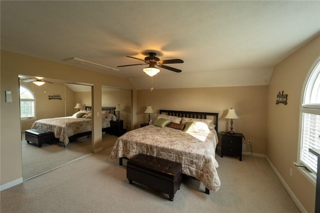 bedroom with multiple closets, lofted ceiling, light colored carpet, and a ceiling fan
