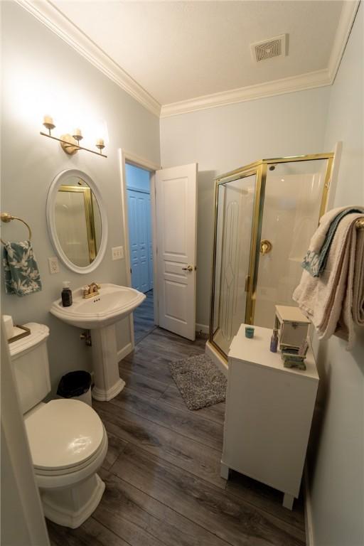 bathroom featuring crown molding, a stall shower, wood finished floors, toilet, and baseboards