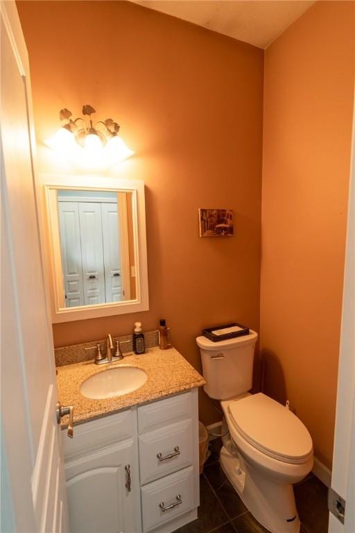 half bathroom with toilet, tile patterned flooring, and vanity