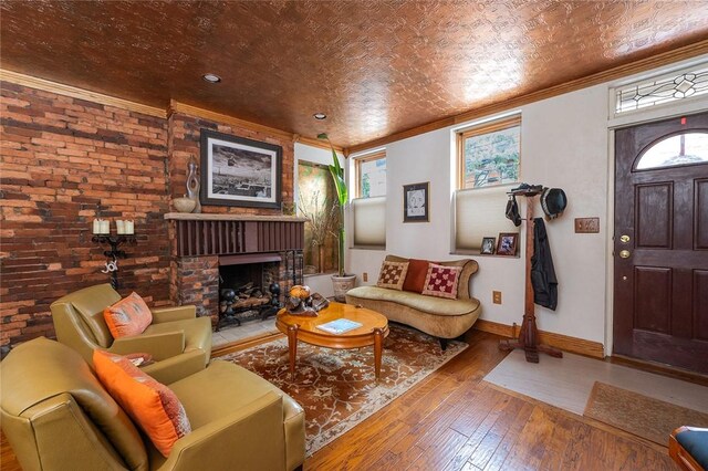 2220 Sarah St, South Side, PA 15203 - living room featuring ornamental molding, hardwood / wood-style floors, baseboards, a brick fireplace, and brick wall