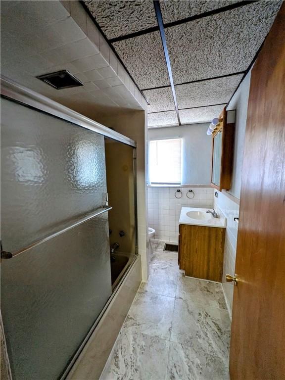 330 Quincy Ave, Mount Oliver, PA 15210 - full bath featuring toilet, vanity, bath / shower combo with glass door, a wainscoted wall, and tile walls