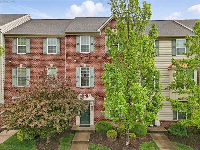 townhome / multi-family property with brick siding and roof with shingles