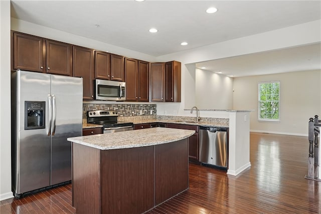 kitchen with appliances with stainless steel finishes, a sink, dark wood finished floors, a peninsula, and recessed lighting