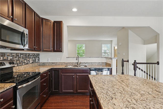 kitchen with appliances with stainless steel finishes, a sink, light stone counters, dark wood-type flooring, and recessed lighting