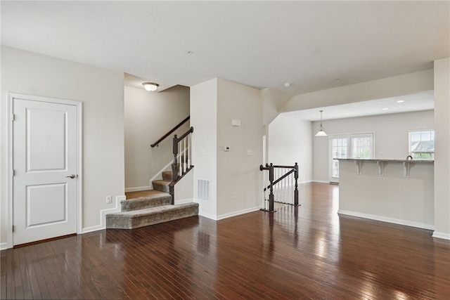 unfurnished living room with hardwood / wood-style flooring and baseboards