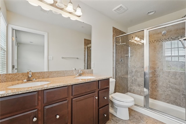 bathroom with a shower stall, toilet, double vanity, and tile patterned floors