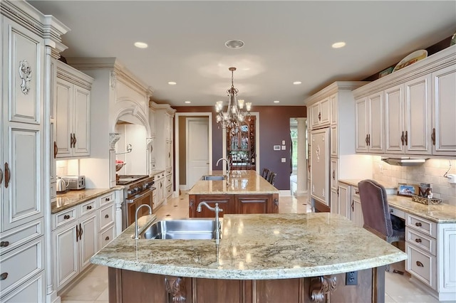 107 Mirage Dr, Cranberry Twp, PA 16066 - kitchen featuring a center island with sink, a sink, high end stove, a chandelier, and tasteful backsplash