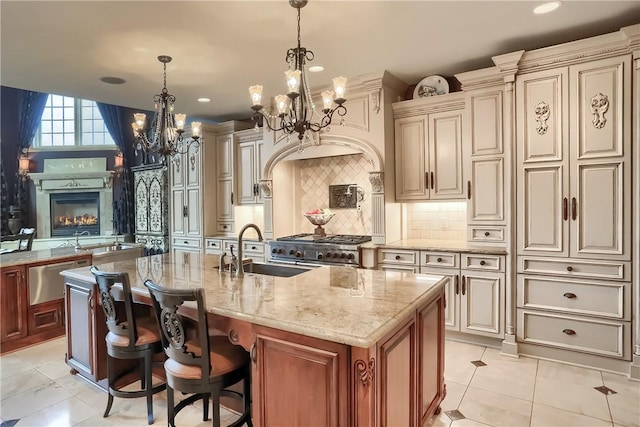 107 Mirage Dr, Cranberry Twp, PA 16066 - kitchen featuring a sink, a chandelier, cream cabinetry, light stone counters, and a kitchen island with sink