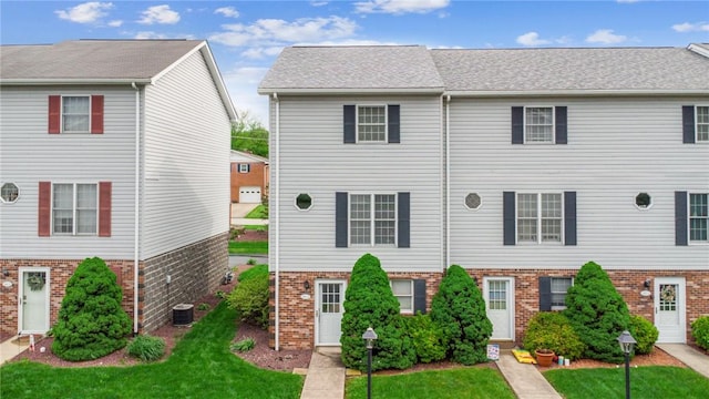 multi unit property featuring brick siding, a front yard, and central AC unit