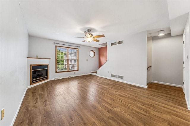 unfurnished living room featuring wood finished floors, ceiling fan, baseboards, and a glass covered fireplace