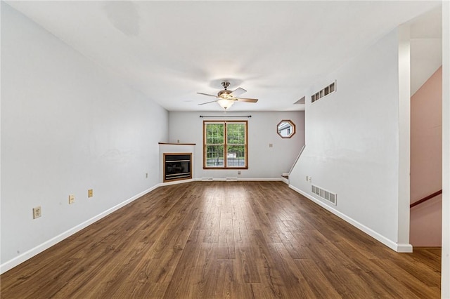 unfurnished living room featuring ceiling fan, dark wood finished floors, baseboards, and a glass covered fireplace