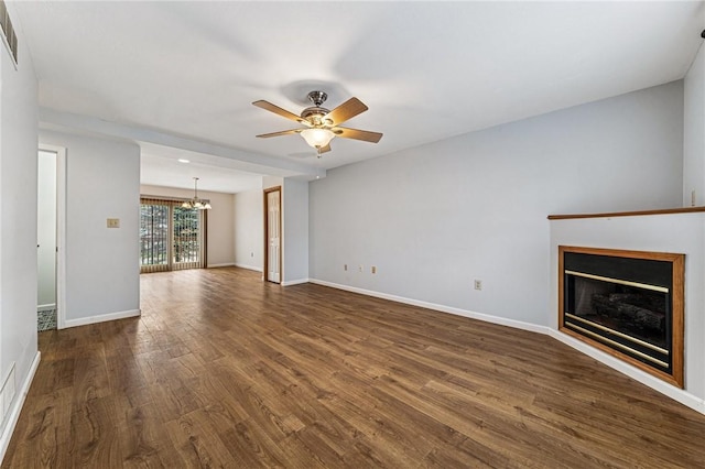 unfurnished living room featuring a chandelier, dark wood-style flooring, a ceiling fan, and baseboards