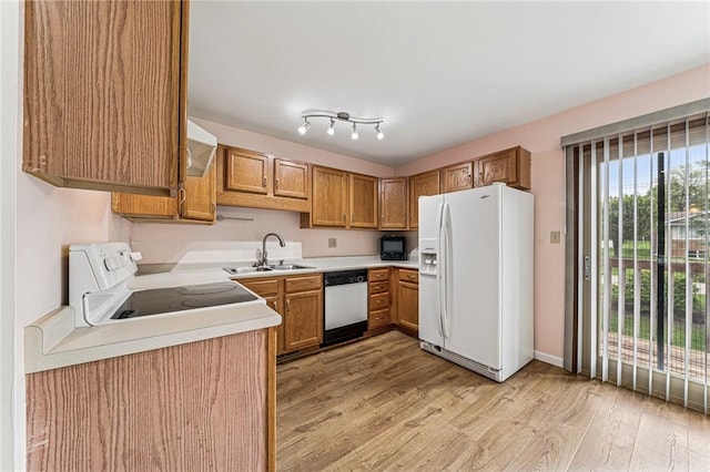 kitchen featuring white appliances, a sink, light wood-type flooring, light countertops, and brown cabinetry