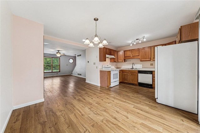 kitchen featuring white appliances, open floor plan, a chandelier, brown cabinetry, and light countertops