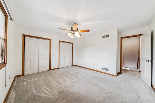 unfurnished bedroom featuring two closets, carpet, baseboards, and ceiling fan