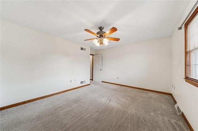 empty room featuring healthy amount of natural light, ceiling fan, carpet, and baseboards