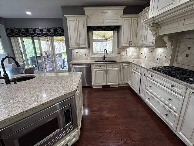 kitchen featuring a sink, appliances with stainless steel finishes, custom range hood, light stone countertops, and recessed lighting