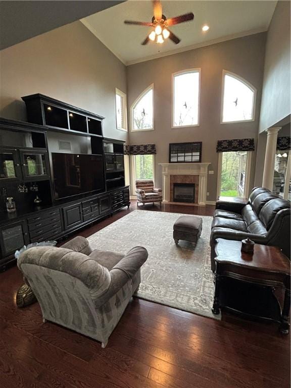 living room featuring high vaulted ceiling, a tiled fireplace, a ceiling fan, hardwood / wood-style floors, and healthy amount of natural light