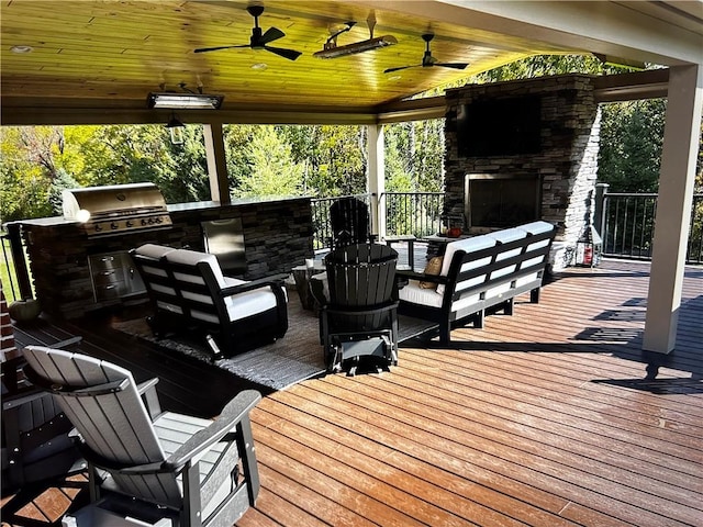 wooden deck featuring exterior kitchen, an outdoor living space with a fireplace, and ceiling fan
