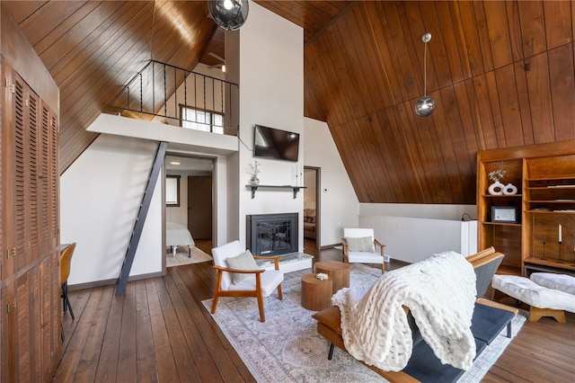 living area featuring wood-type flooring, wooden ceiling, high vaulted ceiling, and a glass covered fireplace