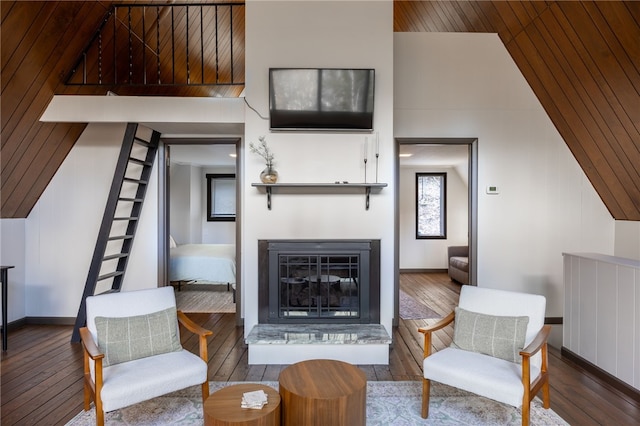 living room featuring wood-type flooring, a glass covered fireplace, wooden ceiling, vaulted ceiling, and baseboards