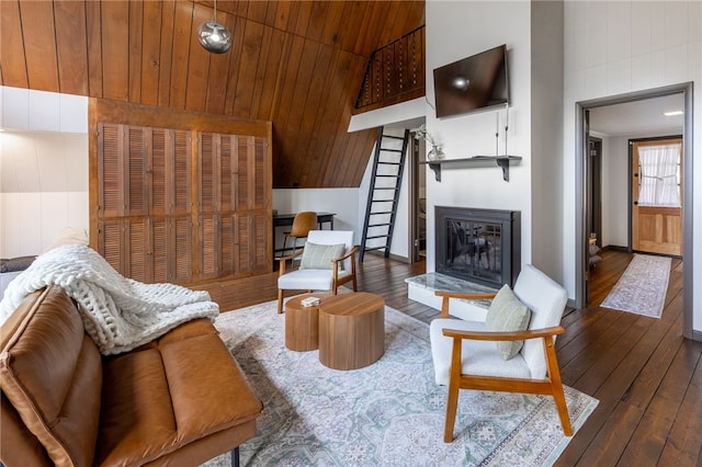 living area with hardwood / wood-style flooring, a glass covered fireplace, and wood walls