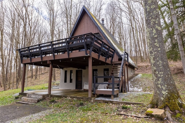 view of front of home with a wooden deck, a patio, and stairway
