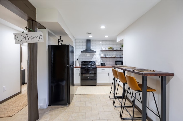 kitchen featuring black appliances, wall chimney exhaust hood, wood counters, backsplash, and white cabinets